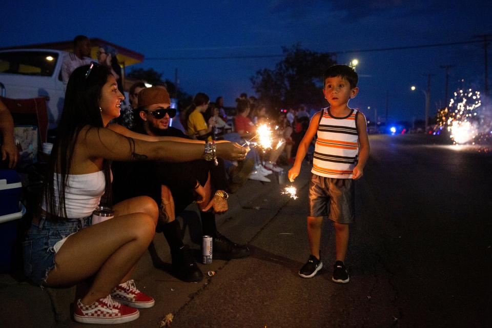 Jocelyn Muñoz hands her brother, Calogero Uranga, a sparkler during the Electric Light Parade on Monday, July 3, 2023, at Apodaca Park.