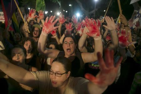 Protesters hold up gloves covered in red during a protest against the violence towards the gay community in Tel Aviv August 1, 2015. REUTERS/Baz Ratner