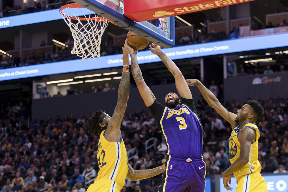 Los Angeles Lakers forward Anthony Davis (3) shoots as Golden State Warriors forward Marquese Chriss, left, and Golden State Warriors guard Andrew Wiggins, right, defend in the first half of an NBA basketball game in San Francisco Saturday, Feb. 8, 2020. (AP Photo/John Hefti)