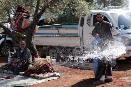 FILE PHOTO: A displaced Syrian pours water in an olive grove in the town of Atmeh, Idlib province, Syria