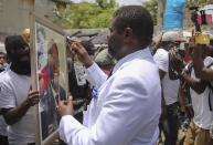 Jimmy Cherizier, alias Barbecue, a former police officer who heads a gang coalition known as "G9 Family and Allies," blesses an image of slain Haitian President Jovenel Moise during a rally to demand justice in Lower Delmas, a district of Port-au- Prince, Haiti Monday, July 26, 2021. Moise was assassinated on July 7 at his home. (AP Photo/Joseph Odelyn)