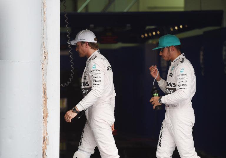 Lewis Hamilton (right) and teammate Nico Rosberg walk back into the garage after Hamilton takes pole position and Rosberg finished third in the qualifying session for the Formula One Malaysian Grand Prix in Sepang on March 28, 2015