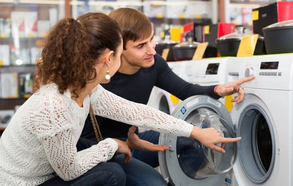 A woman and a man looking at a washing machine in a store