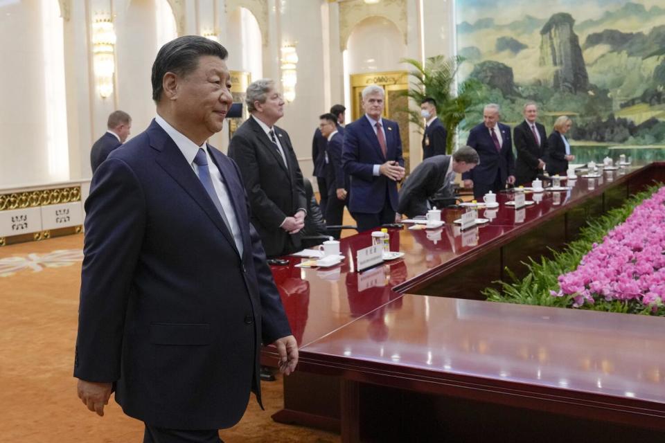 A person walks by a long table where people are standing along one side.