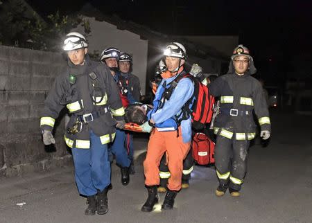 Rescue workers use a stretcher to carry a man who was rescued from a collapsed house in Mashiki town, Kumamoto prefecture, southern Japan, in this photo taken by Kyodo April 15, 2016. Mandatory credit REUTERS/Kyodo