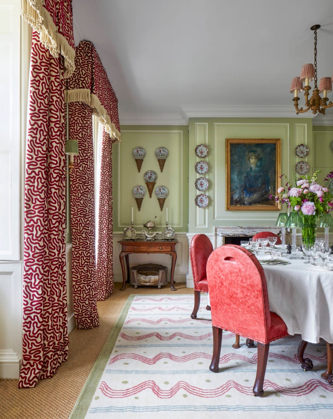 A vibrant, varied mix of reds in worn leather chairs and a picturesque carpet and velvet on silk curtains enlivens the dining room