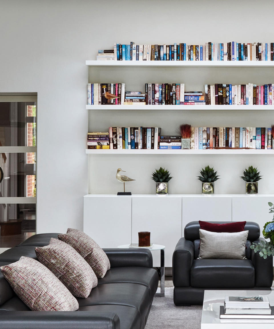 bookshelves in white living room with black leather armchair and couch