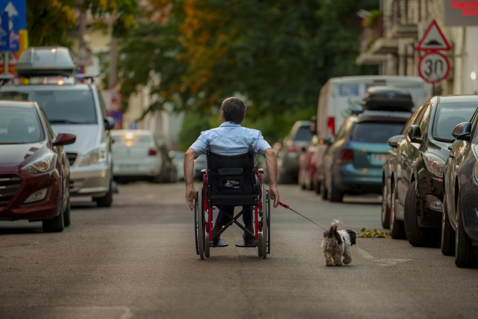 A man walks his dog on a hot evening in Bucharest, Romania, Thursday, July 11, 2024, as temperatures exceeded 39 degrees Celsius (102.2 Fahrenheit). The national weather forecaster issued a red warning for the coming week, as temperatures are expected to exceed 40 degrees Celsius (104 Fahrenheit). (AP Photo/Vadim Ghirda)