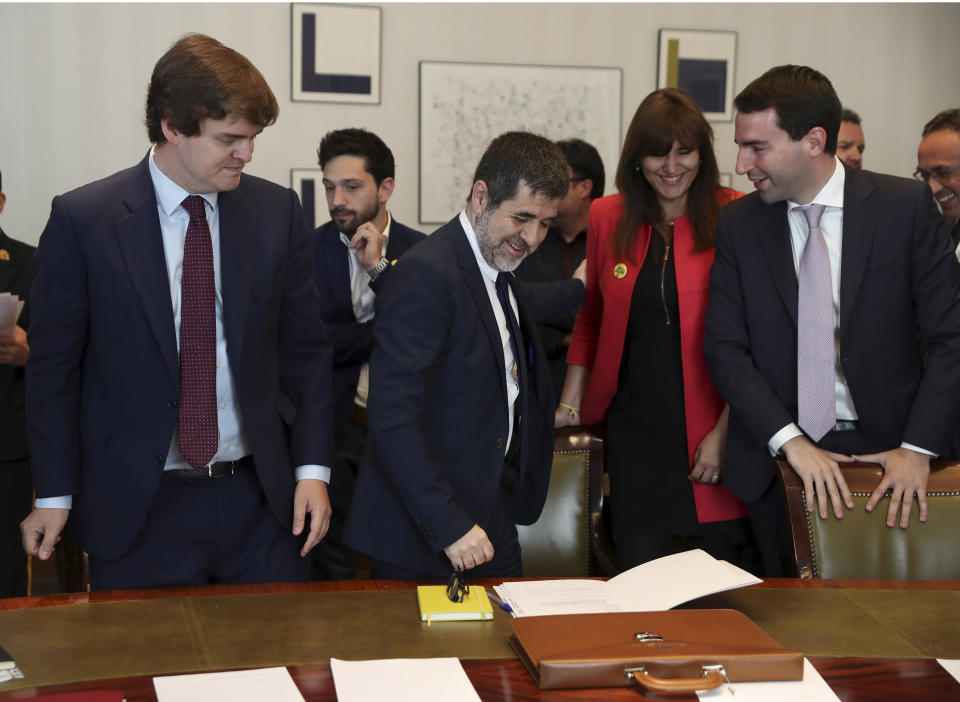 Jordi Sanchez, president of the Catalan National Assembly, center, prepares to sign some documents and collect his credentials inside the Spanish parliament in Madrid, Spain, Monday May 20, 2019. The five separatist leaders on trial for Catalonia's 2017 secession attempt who were elected to the Spanish Parliament in April 28 elections have been escorted by police to pick up their official parliament credentials. The Supreme Court is allowing the five politicians to get their credentials on Monday and attend the opening session of the new Parliament on Tuesday. (J.J. Guillen/Pool Photo via AP)