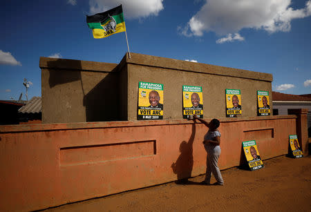 A supporter of President Cyril Ramaphosa's ruling African National Congress (ANC) puts up posters as she awaits election results in Diepkloof township in Johannesburg, South Africa, May 9, 2019. REUTERS/Mike Hutchings