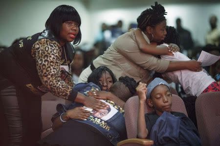 Mourners including Beverly Hassle (L) the cousin of the decedent, and a woman wearing a image of the teenager on her back, cry during the funeral of Demureye "Traydoe" Macon in Chicago, October 8, 2014. REUTERS/John Gress