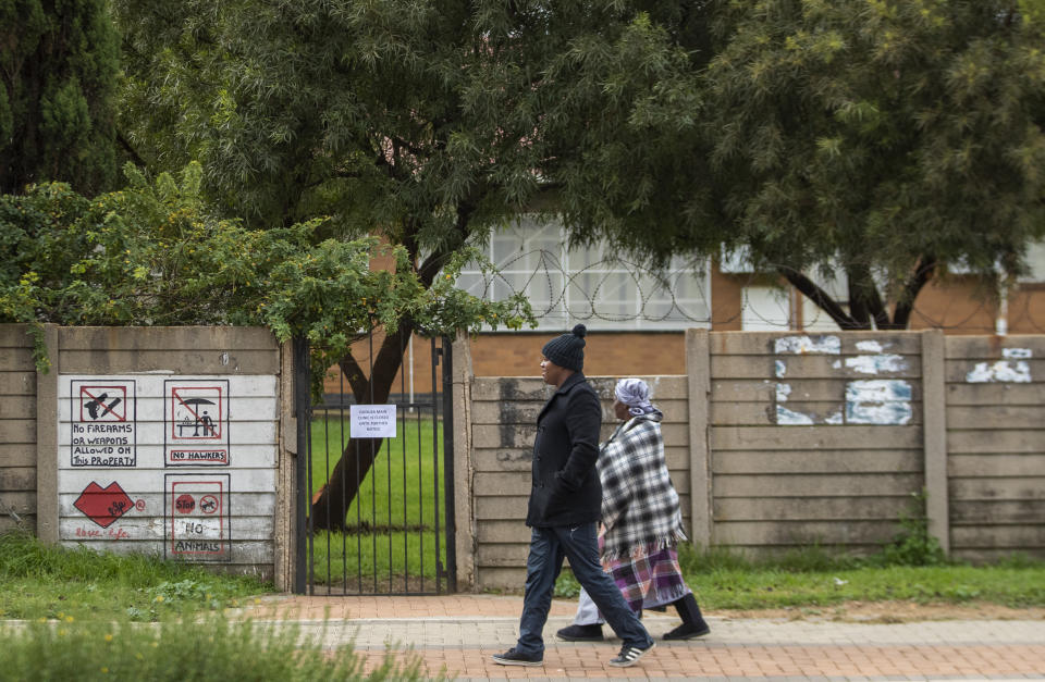 A man and woman walk past an indefinitely closed clinic after a nurse tested positive for Covid-19, in Duduza, east of Johannesburg, South Africa, Thursday, April 2, 2020. South Africa went into a nationwide lockdown for 21 days in an effort to mitigate the spread to the coronavirus. The new coronavirus causes mild or moderate symptoms for most people, but for some, especially older adults and people with existing health problems, it can cause more severe illness or death. (AP Photo/Themba Hadebe)