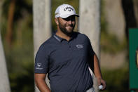 Jon Rahm smiles as he waits to hit on the first tee during the first round of the American Express golf tournament at La Quinta Country Club Thursday, Jan. 20, 2022, in La Quinta, Calif. (AP Photo/Marcio Jose Sanchez)