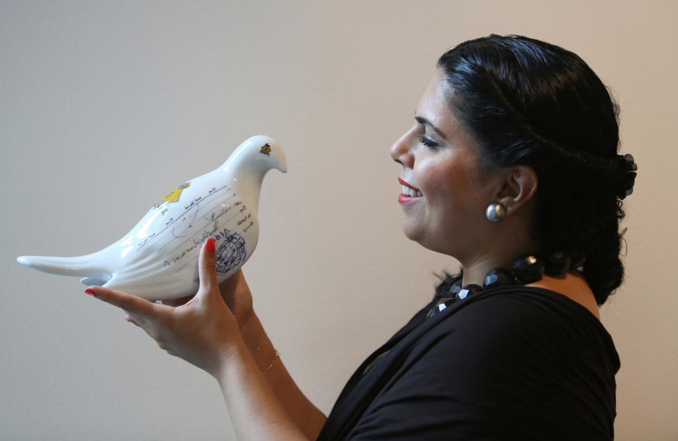 In this Wednesday, March 26, 2014 photo, Saudi artist Manal Al-Dowayan poses with one of her messenger pigeons of "Suspended Together" installation at her exhibition titled "Crash" at the Cuadro Art Gallery in Dubai, United Arab Emirates. The kingdom's modern art scene has become a platform for Saudi artists to voice their frustration about the country’s most sensitive issues without coming into friction with the country’s rulers, reaching the public in new says and allowing individual points of view in a country where dominant ultraconservative norms have long prevailed. (AP Photo/Kamran Jebreili)