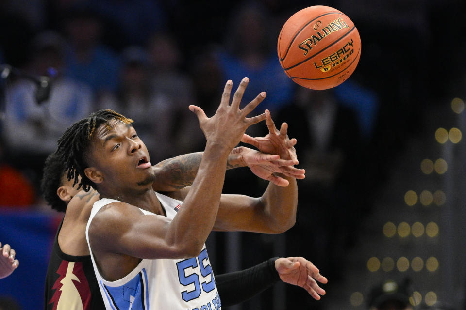 Florida State guard Primo Spears, obscured behind, and North Carolina forward Harrison Ingram reach for the ball during the first half of an NCAA college basketball game in the quarterfinal round of the Atlantic Coast Conference tournament Thursday, March 14, 2024, in Washington. (AP Photo/Nick Wass)