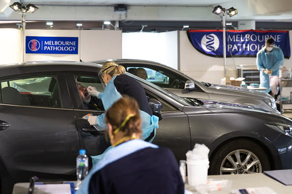 A medical practitioner takes a swab test as she conducts a test for for COVID-19 at an undercover carpark at the Chadstone Shopping Centre in Melbourne.