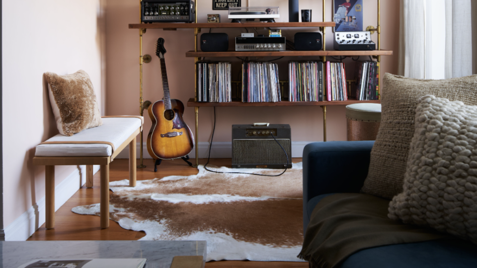 studio apartment ideas, room with shelves full of things and a guitar on the floor and wall