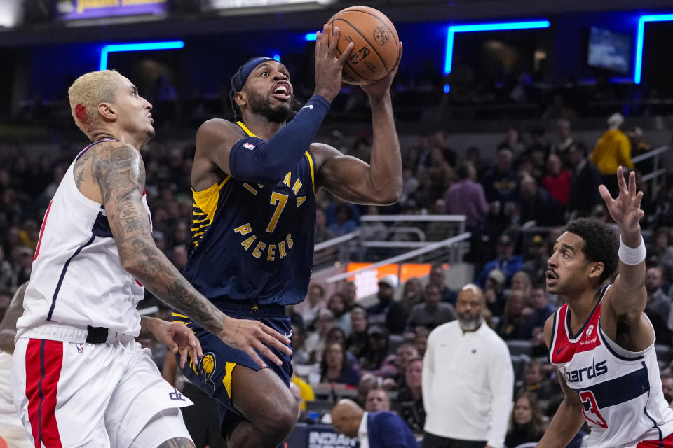 Indiana Pacers guard Buddy Hield (7) shoots between Washington Wizards forward Kyle Kuzma (33) and guard Jordan Poole (13) during the first half of an NBA basketball game in Indianapolis, Wednesday, Oct. 25, 2023. (AP Photo/Michael Conroy)