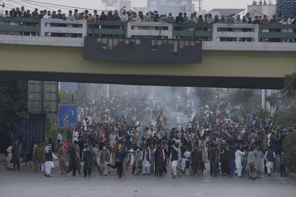 Supporters of former Pakistani Prime Minister Imran Khan's party, 'Pakistan Tehreek-e-Insaf' throw stones toward police officers during a protest to condemn a shooting incident on their leader's convoy, in Rawalpindi, Pakistan, Friday, Nov. 4, 2022. Khan who narrowly escaped an assassination attempt on his life the previous day when a gunman fired multiple shots and wounded him in the leg during a protest rally is listed in stable condition after undergoing surgery at a hospital, a senior leader from his party said Friday. (AP Photo/Mohammad Ramiz)