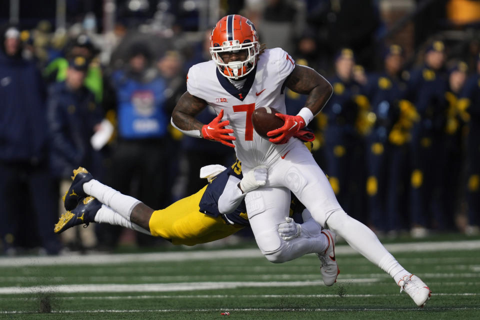 Illinois wide receiver Brian Hightower (7) evades Michigan defensive back Rod Moore (19)in the first half of an NCAA college football game in Ann Arbor, Mich., Saturday, Nov. 19, 2022. (AP Photo/Paul Sancya)