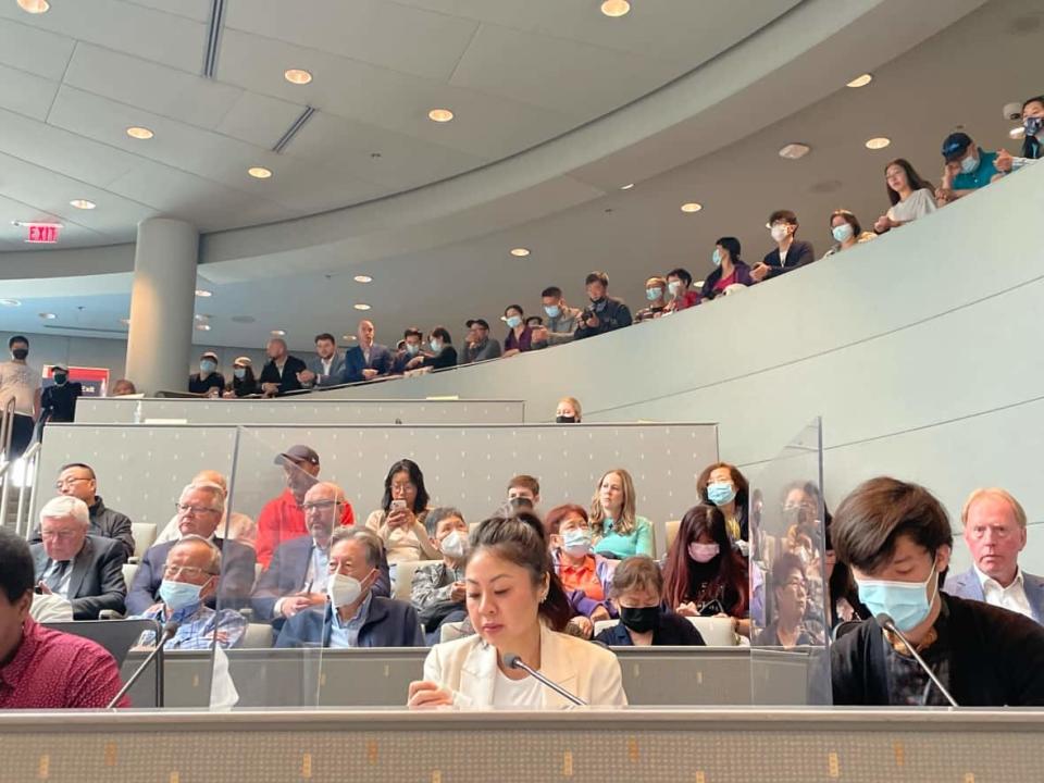 Christina Trang, at the centre in white, speaks through tears at Tuesday's city council meeting.  (Wallis Snowdon/CBC - image credit)