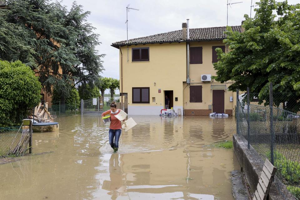 A woman carries her belongings in a flooded area near Bologna, Italy, Thursday, May 18, 2023. Rescue crews worked Thursday to reach towns and villages in northern Italy that were cut off from highways, electricity and cell phone service following heavy rains and flooding, as farmers warned of “incalculable” losses and authorities began mapping out cleanup and reconstruction plans. (Guido Calamosca/LaPresse via AP)