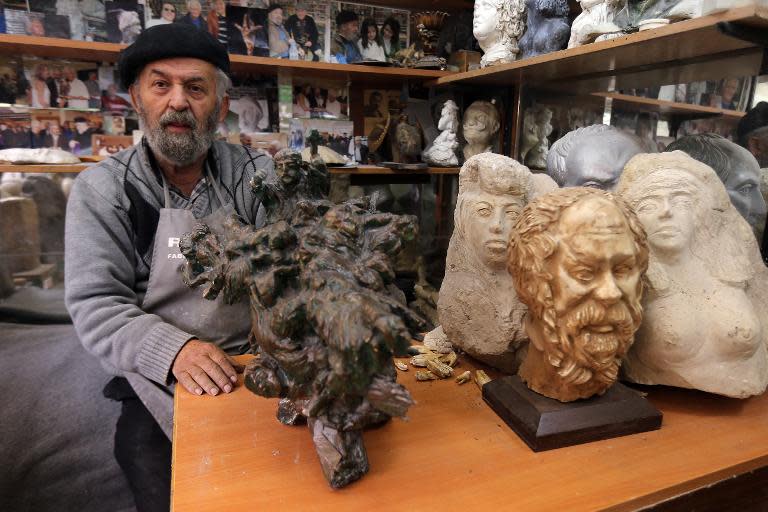 Ashod Tazian, a 79-year-old Lebanese-Armenian sculptor whose family fled mass killings of Armenians under the Ottoman Empire in 1915, sits next to his artwork in Beirut on April 16, 2015