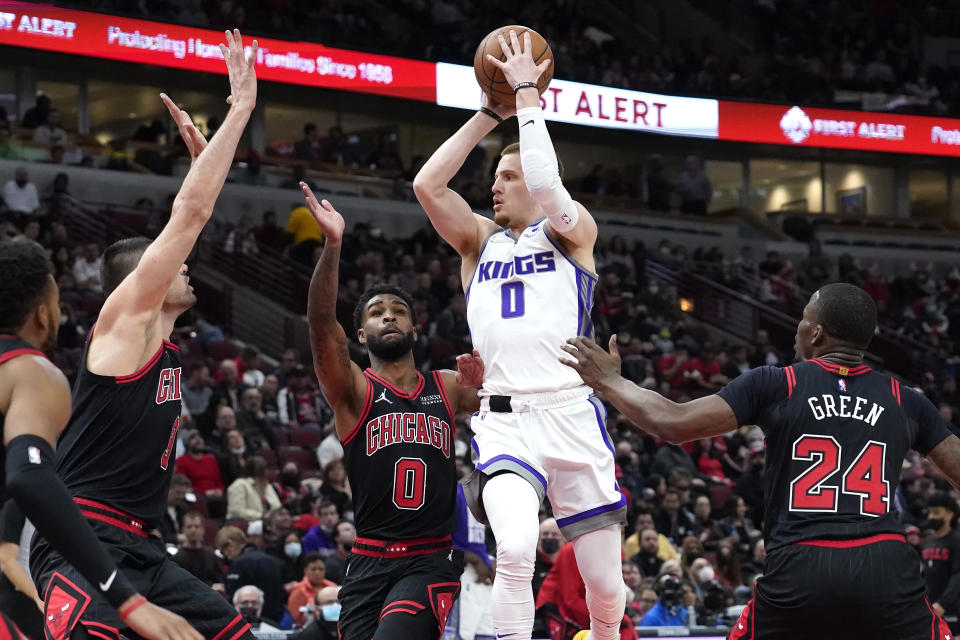 Sacramento Kings' Donte DiVincenzo passes under pressure from Chicago Bulls' Nikola Vucevic, left, Coby White (0) and Javonte Green during the first half of an NBA basketball game Wednesday, Feb. 16, 2022, in Chicago. (AP Photo/Charles Rex Arbogast)