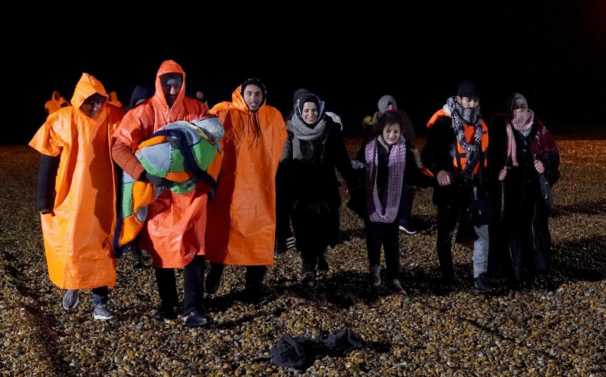 A group of people thought to be migrants walk on the beach at Dungeness, in Kent, after being rescued by the RNLI in the Channel on Saturday - Gareth Fuller/PA Wire