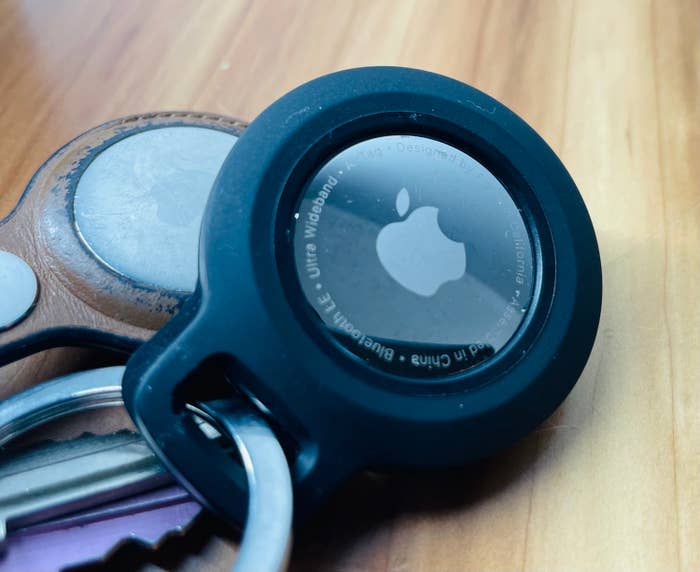 Close-up of a keychain with an Apple AirTag and a leather keychain on a wooden surface