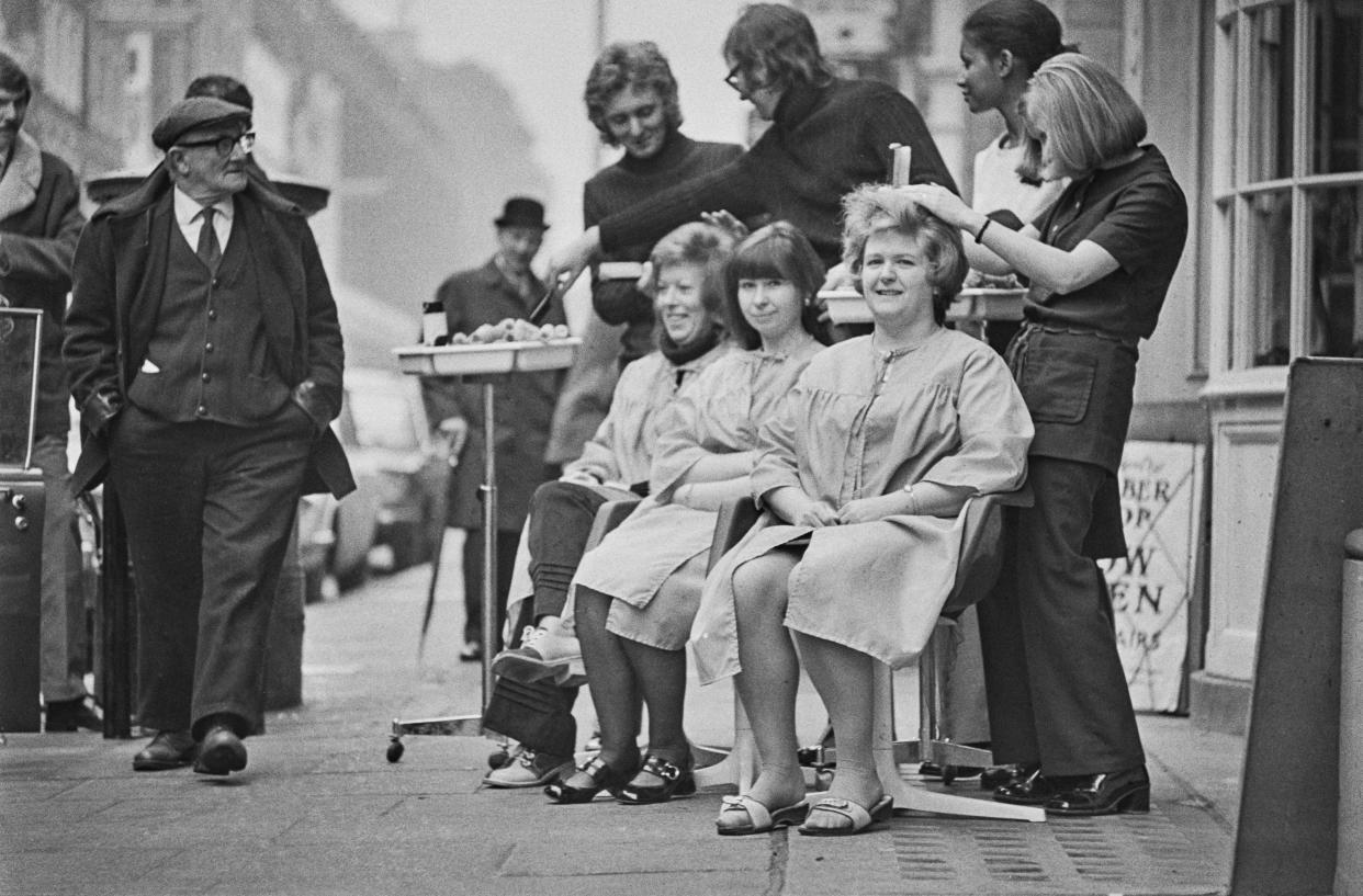 Customers having their hair cut on the pavement in Hatton Garden, London, due to power cuts following a miners' strike, UK, 17th February 1972.  (Photo by Evening Standard/Hulton Archive/Getty Images)