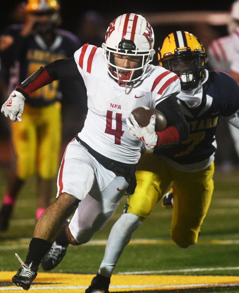 NFA's Jonathan Mercado gets by Ledyard's James Green for a gain during NFA's 19-14 win over Ledyard at Bill Mignault Field in Ledyard.