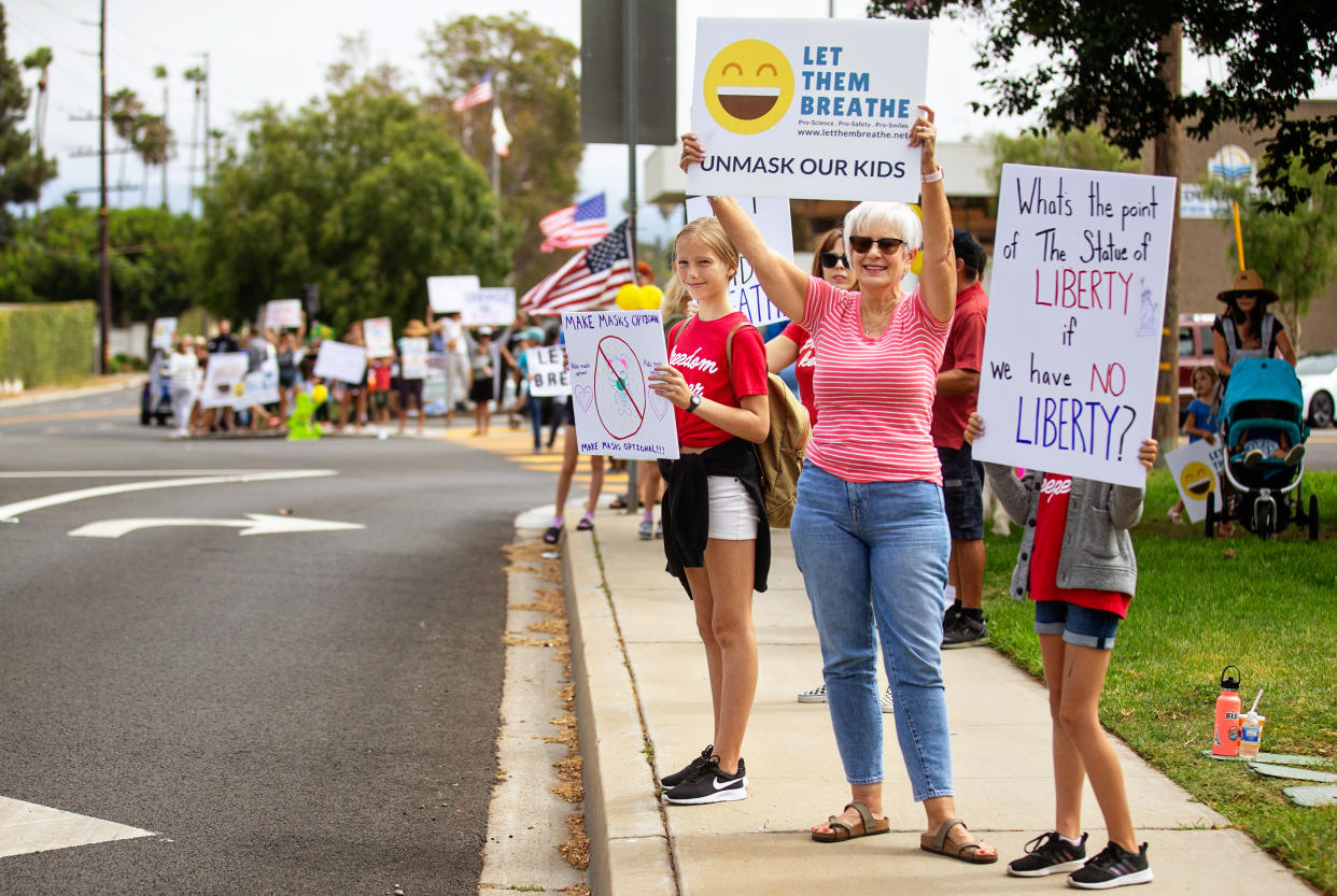 Protesters stand on the side of a road holding signs reading: Let them breathe and What's the point of the Statue of Liberty if we have no liberty?