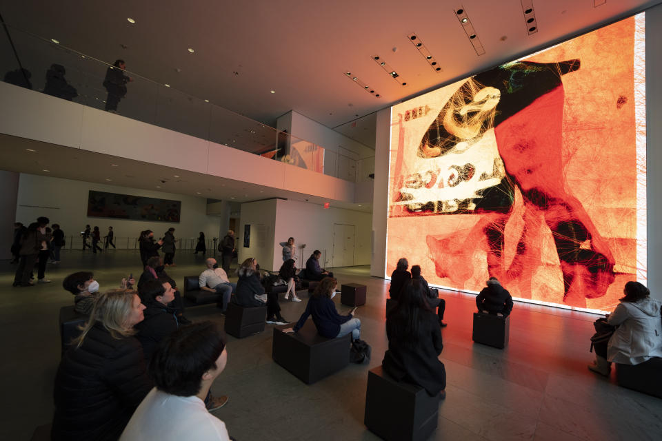 Visitors look at artist Refik Anadol's "Unsupervised" exhibit at the Museum of Modern Art, Wednesday, Jan. 11, 2023, in New York. The new AI-generated installation is meant to be a thought-provoking interpretation of the New York City museum's prestigious collection. (AP Photo/John Minchillo)