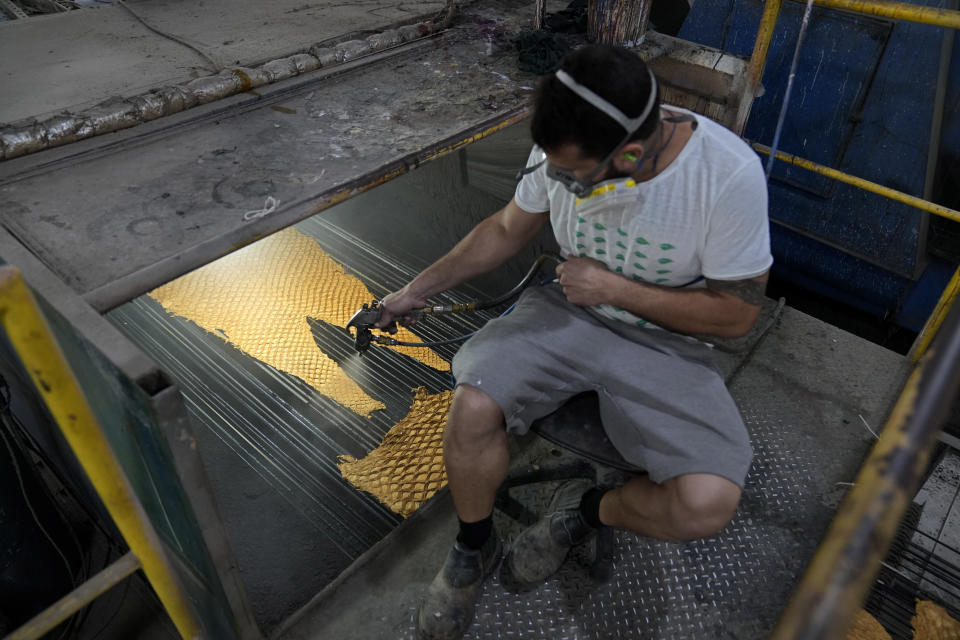 A worker treats a pirarucu skin at the Nova Kaeru tannery factory in Tres Rios municipality, Rio de Janeiro state, Brazil, Tuesday, Oct. 11, 2022. Thousands of miles away from the Amazon, down a hilly dirt road on the outskirts of Rio de Janeiro, Nova Kaeru will process about 50,000 skins from legally-caught giant pirarucu or arapaima fish this year. (AP Photo/Silvia Izquierdo)