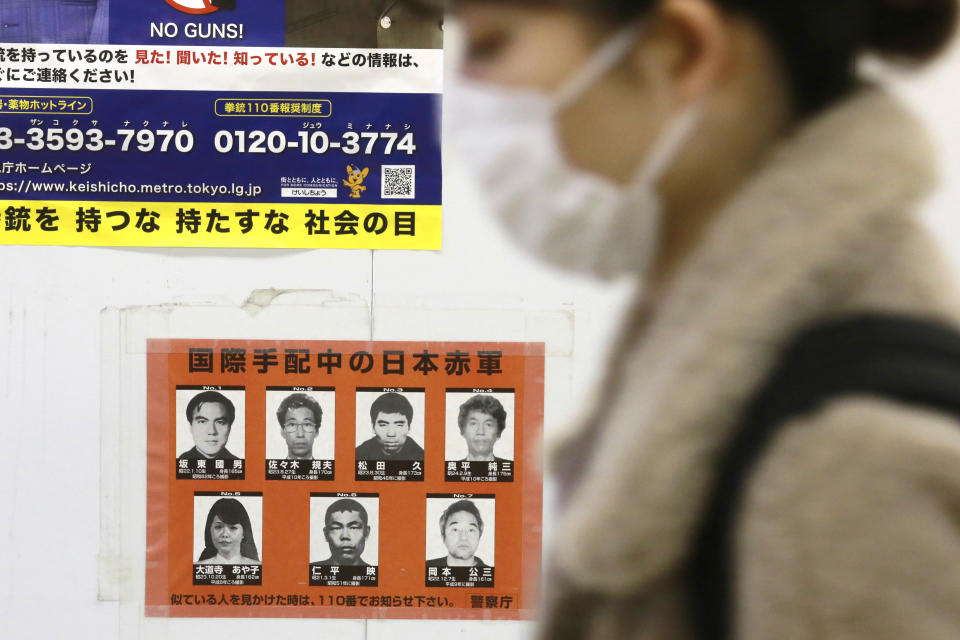 A woman walks past a poster of wanted Japanese terrorists in Tokyo, Tuesday, Feb. 15, 2022. Tokyo police on Monday stepped up the hunt for members of the Japanese Red Army wanted for their alleged role in attacks in the 1970s and 1980s, releasing a video with images of the aging militants that warned the “case” was not over yet. (AP Photo/Koji Sasahara)