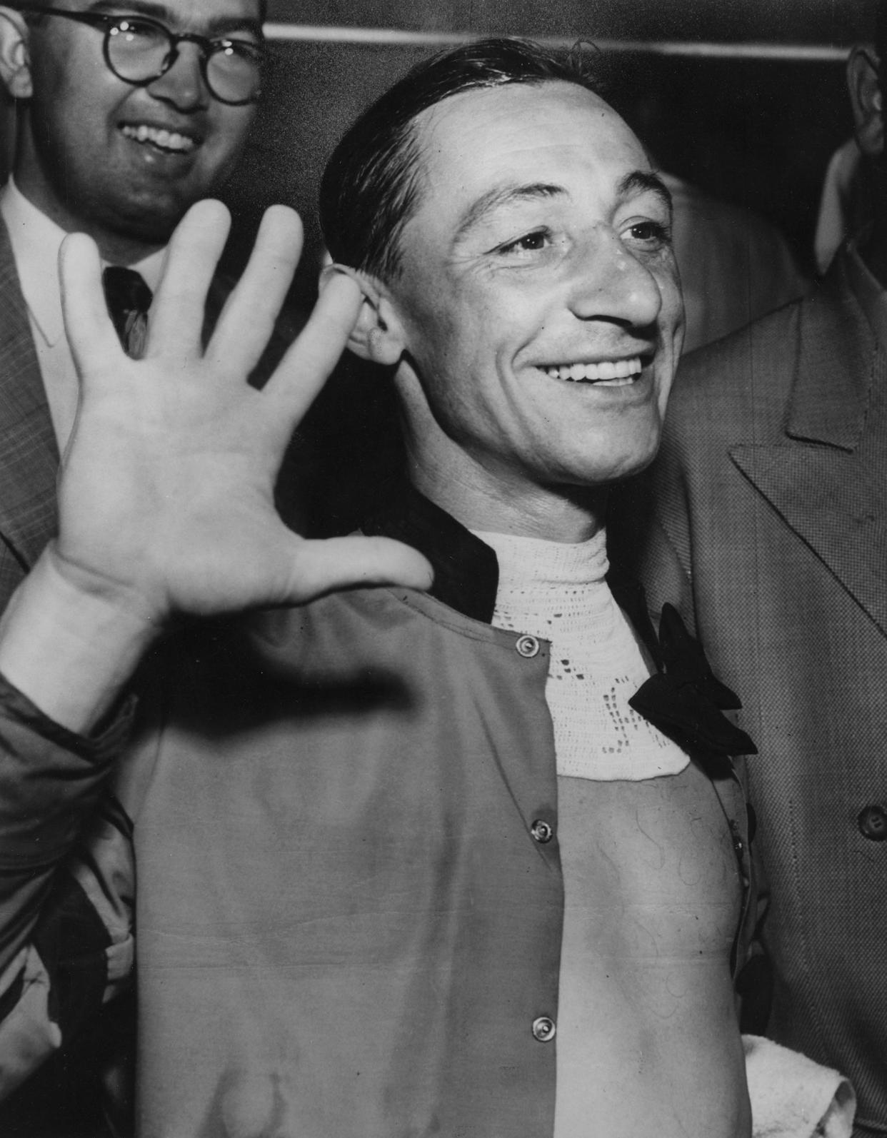 Jockey Eddie Arcaro holds up five fingers for each of the five winners he had ridden in the Kentucky Derby, after bringing Hill Gail home to victory in the 1952 race.