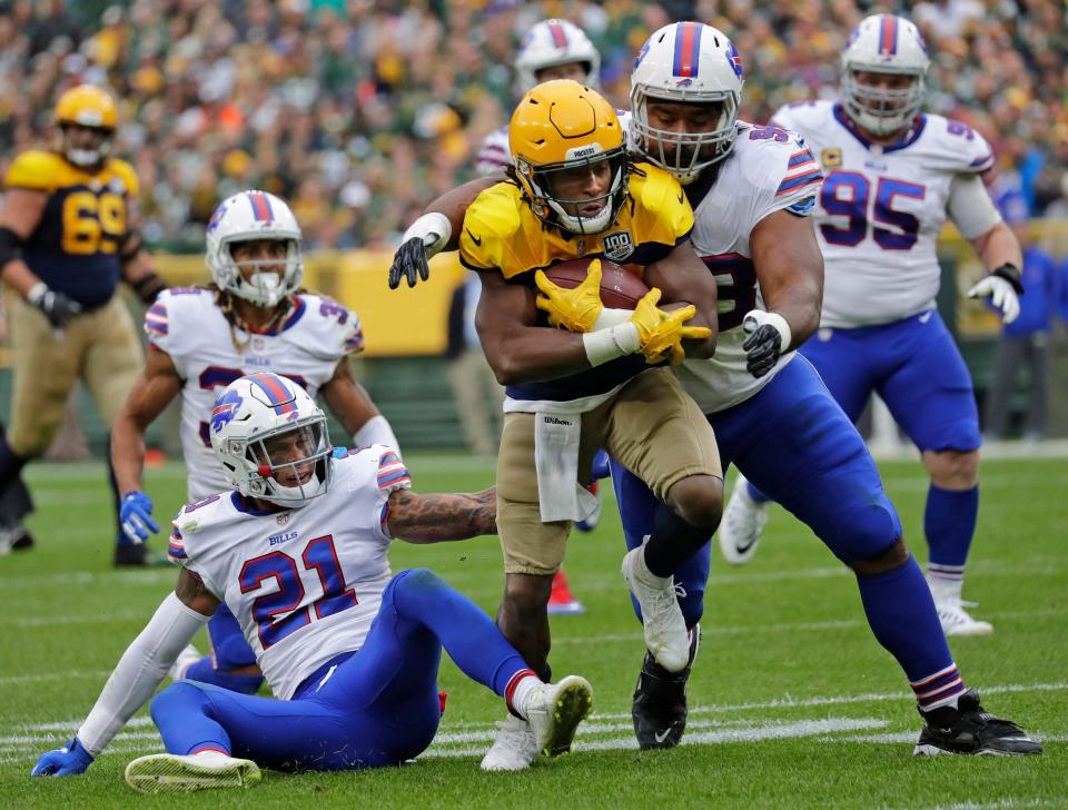 Green Bay Packers running back Aaron Jones (33) carries the ball as Buffalo Bills defensive back Jordan Poyer (21) and defensive tackle Star Lotulelei (98) defend during the second quarter of a game on Sept. 30, 2018, at Lambeau Field.