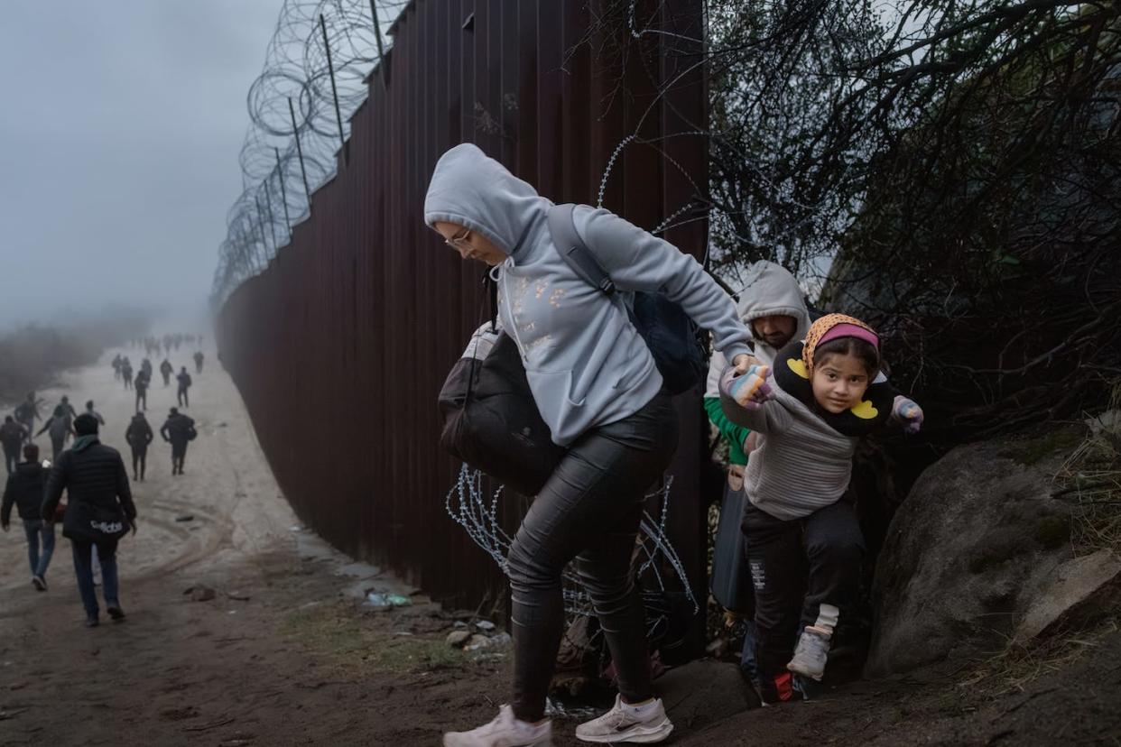 Migrants cross through a gap in the U.S.-Mexico border fence on Dec. 22, 2023, in Jacumba Hot Springs, Calif. <a href="https://www.gettyimages.com/detail/news-photo/migrants-cross-through-a-gap-in-the-us-mexico-border-fence-news-photo/1876398355?adppopup=true" rel="nofollow noopener" target="_blank" data-ylk="slk:Qian Weizhong/VCG via Getty Images;elm:context_link;itc:0;sec:content-canvas" class="link ">Qian Weizhong/VCG via Getty Images</a>