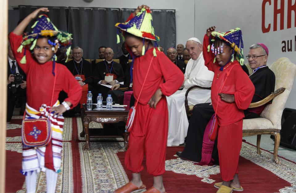 Pope Francis looks at children dancing during a visit to the diocesan Caritas center in Rabat, Morocco, Saturday, March 30, 2019. Francis's weekend trip to Morocco aims to highlight the North African nation's tradition of Christian-Muslim ties while also letting him show solidarity with migrants at Europe's door and tend to a tiny Catholic flock on the peripheries. (AP Photo/Gregorio Borgia)