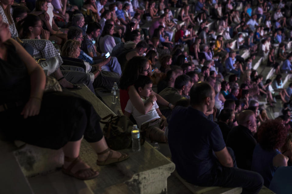 A woman hugs her child during a concert at Odeon of Herodes Atticus in Athens, on Wednesday, July 15, 2020. Greek Culture Ministry allowed the ancient theaters of Epidaurus in southern Greece and Herodes Atticus in Athens to host performances under strict safety guidelines due the COVID-19 pandemic.(AP Photo/Petros Giannakouris)