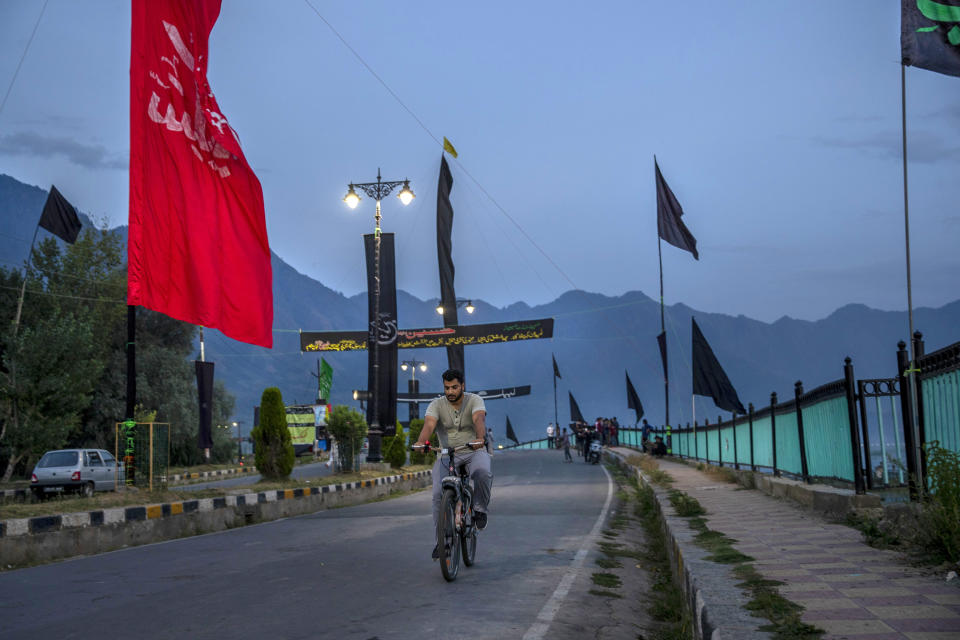 A Kashmiri man cycles past religious banners and flags erected by Shiite Muslims to commemorate Muharram on a deserted street on the outskirts of Srinagar, Indian controlled Kashmir, Tuesday, Aug. 25, 2020. Observing the Muslim month of Muharram, which marks the martyrdom of the Prophet Muhammad’s grandson in the battle of Karbala, is an article of faith. But as the coronavirus spreads in Indian-controlled Kashmir, Shiite Muslims prefer to commemorate the holy days inside their home following the advice of religious scholars and health experts in the disputed region’s main city. (AP Photo/ Dar Yasin)