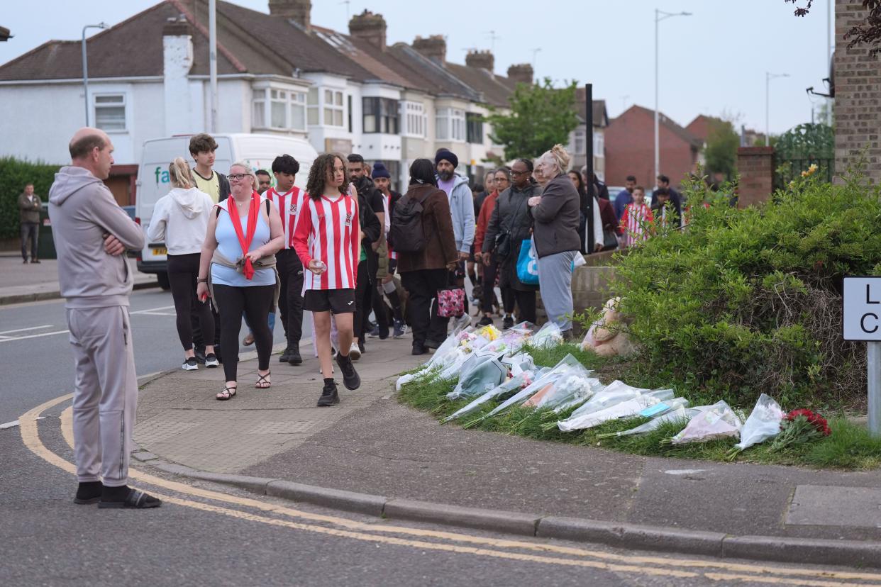 File photo dated 1/05/24 of members of the community, including River Hawks FC, looking at floral tributes in Hainault, north-east London, where 14-year-old Daniel Anjorin was killed in a sword attack on Tuesday that saw four others injured, including two Metropolitan Police officers. A 36-year-old man is to appear in court charged with murdering a 14-year-old boy in a sword rampage in east London. Marcus Aurelio Arduini Monzo will appear at Barkingside Magistrates' Court, having been charged by police on Wednesday evening. Issue date: Thursday May 2, 2024.