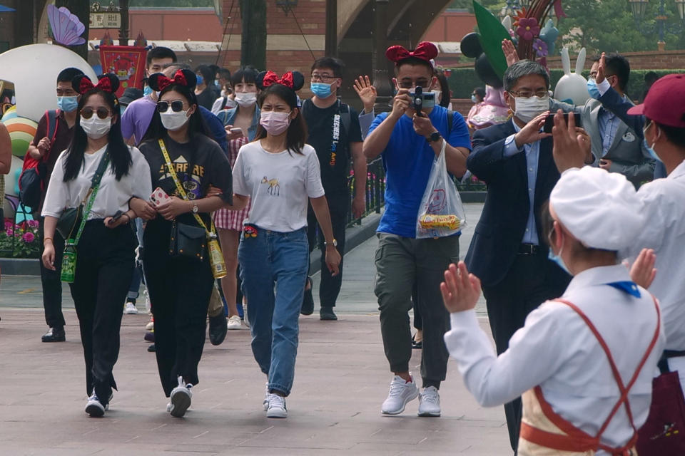 Visitors, wearing face masks, enter the Disneyland theme park in Shanghai as it reopened, Monday, May 11, 2020. Visits will be limited initially and must be booked in advance, and the company said it will increase cleaning and require social distancing in lines for the various attractions. With warmer weather and new coronavirus cases and deaths falling to near-zero, China has been reopening tourist sites such as the Great Wall and the Forbidden City palace complex in Beijing.(AP Photo/Sam McNeil)