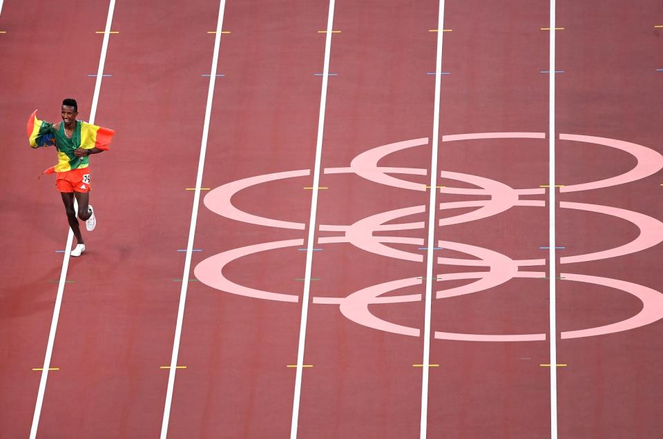 Ethiopia's Selemon Barega carries the flag of his country after winning gold in the men's 10,000-meter race.