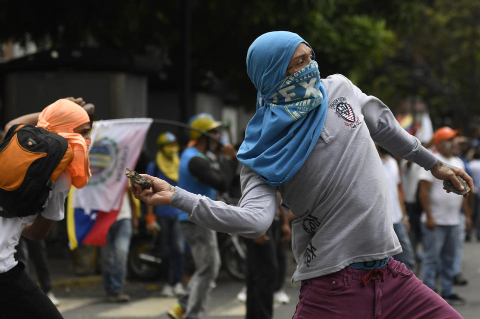 A supporter of opposition political leader Juan Guaido hurls stones at police blocking a march in Caracas, Venezuela, Tuesday, March 10, 2020. Guaido called for the march aimed at retaking the National Assembly legislative building, which opposition lawmakers have been blocked from entering. (AP Photo/Matias Delacroix)