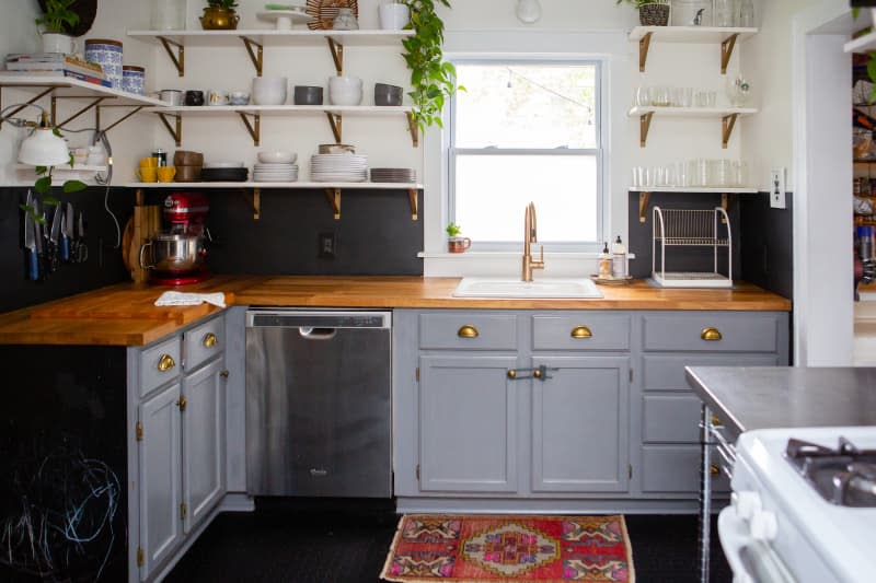 gray kitchen features open shelving and a red rug