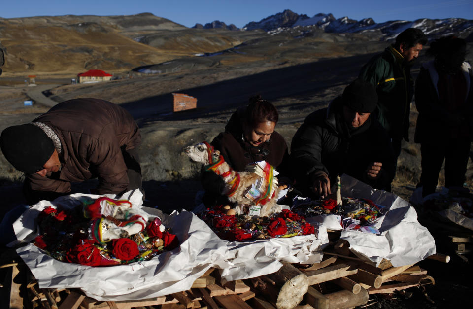 People prepare their offerings to be sacrificed by fire as part of the ceremony for "Pachamama," or "Mother Earth," on La Cumbre, a mountain that is considered scared ground, on the outskirts of La Paz, Bolivia, Friday, Aug. 1, 2014. The month of August is the time people gather in the mountains of Bolivia to make offerings in honor of the earth goddess and ask for good fortune. According to local agrarian tradition, Mother Earth awakes hungry and thirsty in August and needs offerings of food and drink in order for to be fertile and yield abundant crops. (AP Photo/Juan Karita)