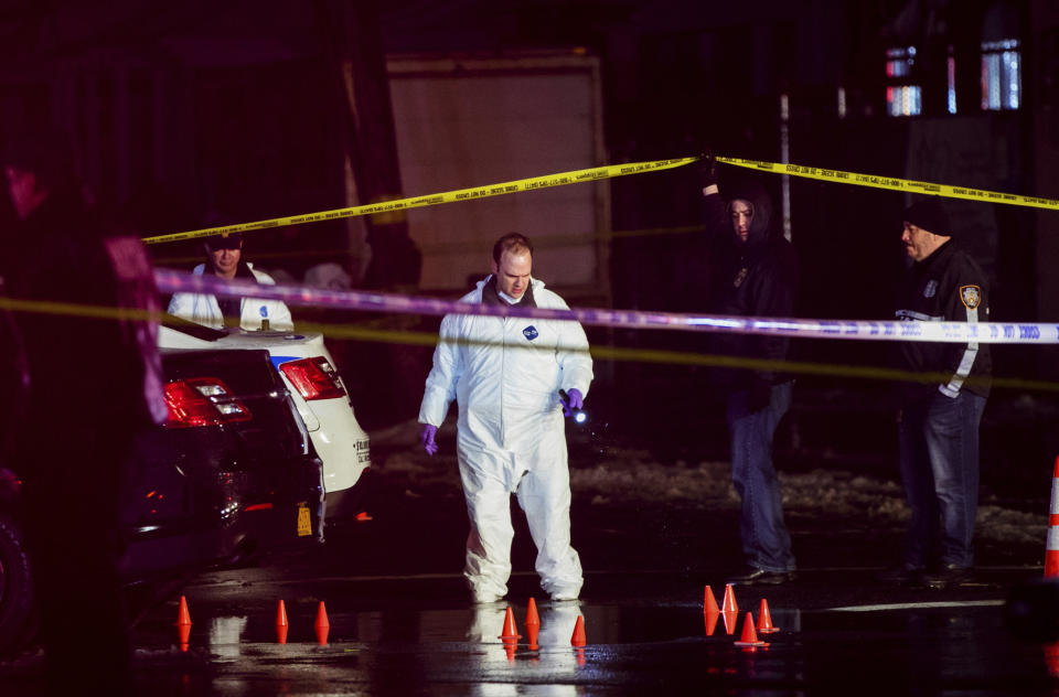 Investigators look over the area after a few New York City police officers were shot while responding to a robbery at a T-Mobile store in the Queens borough of New York on Tuesday, Feb. 12, 2019. (AP Photo/Kevin Hagen)