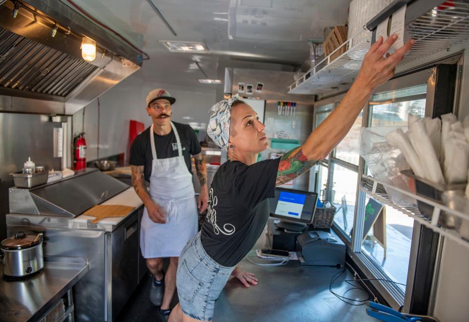 Chase Gilroy and Jess McAtee, owners of Flour-ish Comfort Food Truck, prepare orders Saturday.